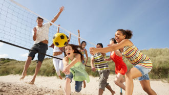 a photo of teenagers playing volleyball on a beach