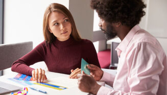 a woman putting colored overlays on a paper as she talks to her teacher