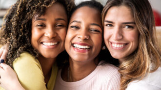 three smiling women pose cheek to cheek