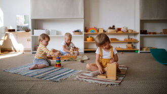 a group of young children of varying ages playing on the floor with blocks