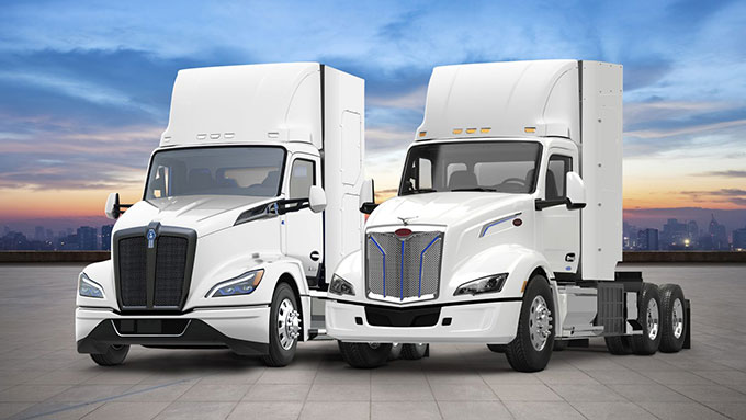 two unhitched white tractor-trailers parked next to each other in front of a sunset sky