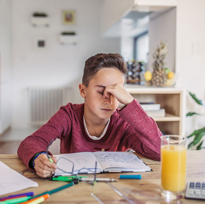 a kid sitting at a table studying and looking really stressed out