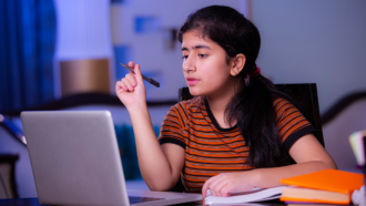 a photo of a girl studying in front of a laptop