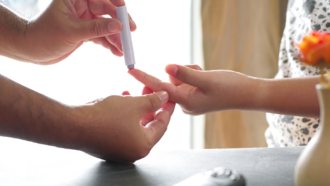 a closeup of a person having their index finger pricked to test their blood-sugar level