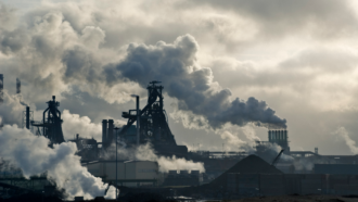 smoke stacks in an urban area pump pollution into the sky